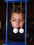 Bernoulli's Principle states that when air is flowing, it has less pressure.  Thus when this young man blows between the two golf balls, they COME TOGETHER!