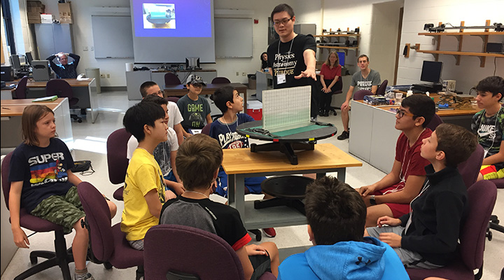 Graduate student Xuhui Zhou talks about microfluidics with students.