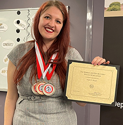 Faith Bergin, seen here accepting the Margie and Don Bottorff Physics Scholarship at a ceremony last year, has racked up medals for competitive dance. She is wearing three medals earned at 2022 Nationals which qualified her as a nationally ranked collegiate ballroom dancer. 